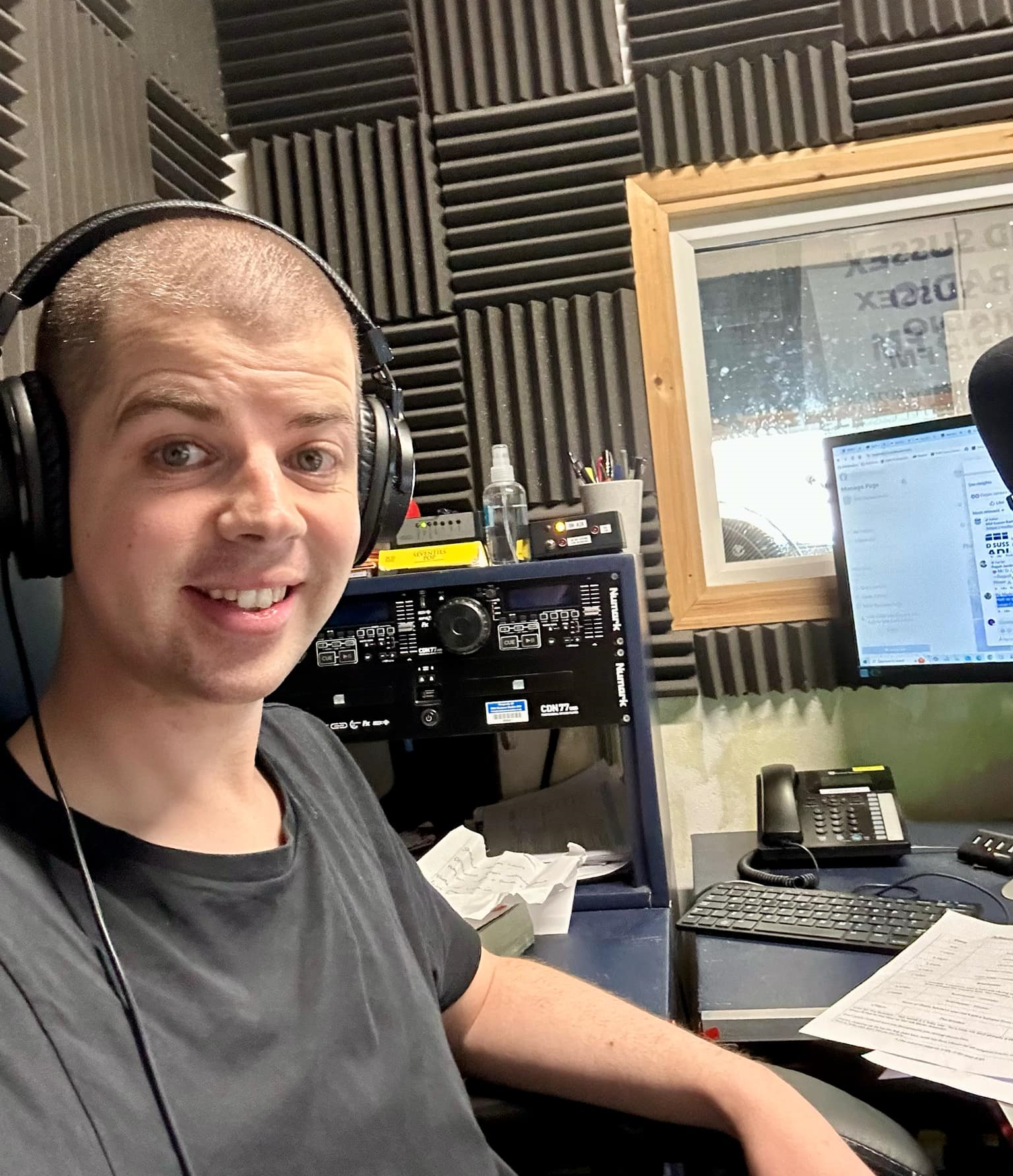 Ryan wearing headphones in soundproof studio, with audio equipment, monitor, and acoustic foam panels behind.